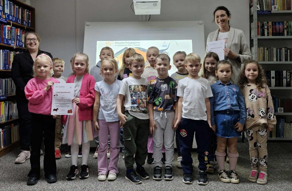 Na zdjęciu widać grupę dzieci stojących w bibliotece wraz z dwiema osobami dorosłymi – bibliotekarką i nauczycielką. W tle wyświetlany jest slajd z logo Biblioteki Pedagogicznej w Ciechanowie Filia w Pułtusku.

Dzieci trzymają w rękach dyplomy – na pierwszym planie widoczny jest plakat z napisem „Podziękowanie”. Cała grupa wygląda na zadowoloną i dumą z udziału w zajęciach.

Zdjęcie przedstawia moment podsumowania spotkania edukacyjnego, prawdopodobnie warsztatów lub zajęć bibliotecznych, podczas którego dzieci otrzymały oficjalne podziękowania i pamiątkowe dyplomy.