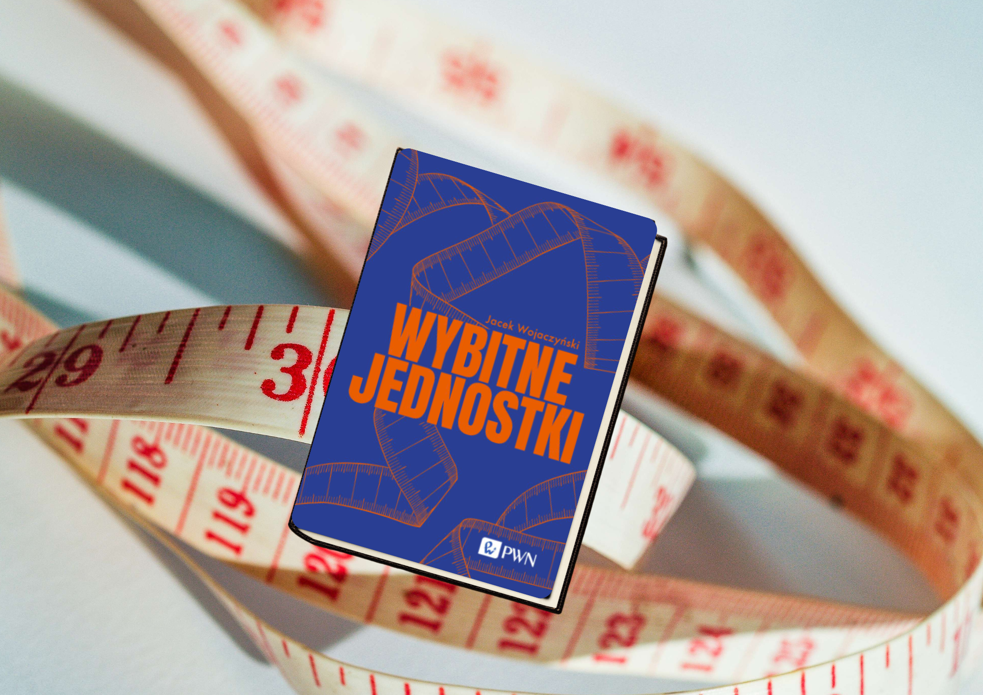 Na grafice przedstawiono książkę Wybitne jednostki autorstwa Jacek Wojaczynski, umieszczoną na tle rozwiniętej taśmy mierniczej. Centralnym elementem ilustracji jest okładka książki w intensywnym granatowym kolorze. Widnieje na niej duży, pomarańczowy tytuł „Wybitne jednostki”, zapisany pogrubioną, nowoczesną czcionką. Nad tytułem umieszczono nazwisko autora, a w dolnej części znajduje się logo wydawnictwa PWN. Tło okładki zdobi subtelny rysunek zwiniętej taśmy mierniczej, który stanowi graficzne nawiązanie do tematyki jednostek miary i pomiarów. Tłem całej kompozycji jest rozwinięta taśma krawiecka z wyraźnie widocznymi czerwonymi oznaczeniami liczbowymi i podziałką centymetrową. Taśma tworzy miękkie, falujące linie otaczające książkę, dzięki czemu kompozycja nabiera dynamiki i głębi. Rozmyte tło sprawia, że wzrok odbiorcy koncentruje się przede wszystkim na publikacji. Kolorystyka grafiki opiera się na kontrastowym zestawieniu granatu i pomarańczu z jasnym tłem oraz czerwonymi oznaczeniami na taśmie mierniczej. Motyw miarki jednoznacznie kojarzy się z mierzeniem, jednostkami długości i precyzją, doskonale współgrając z tytułem książki. Całość ma nowoczesny i estetyczny charakter. Grafika skutecznie przyciąga uwagę oraz sugeruje, że publikacja dotyczy zagadnień związanych z jednostkami miary, pomiarami lub szerzej rozumianą nauką i matematyką.